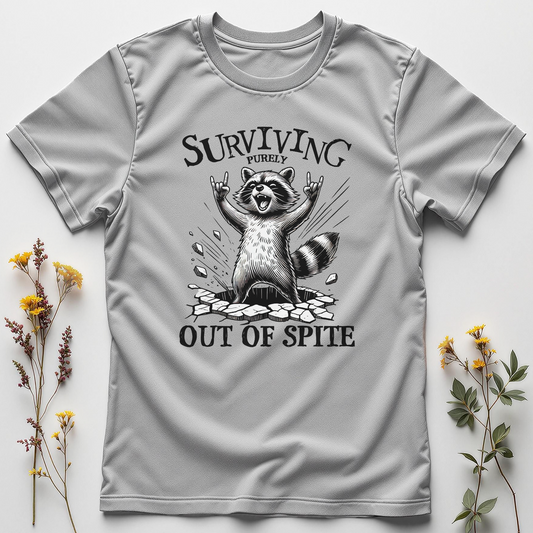 Gray t-shirt with a raccoon graphic and text 'Surviving Out of Spite' on a light gray background with flowers.